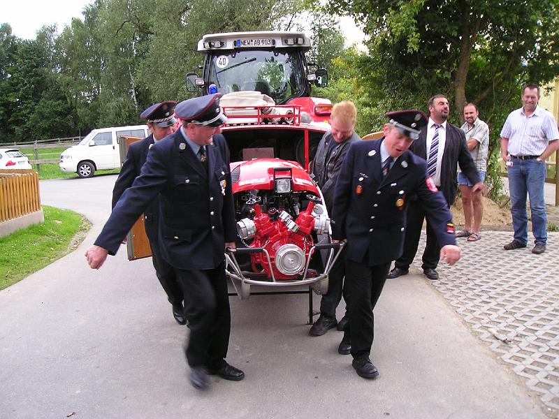 Pumpentraeger.JPG - MIt vereinten Kräften wird die neue Pumpe vom Anhänger geholt, voran die Kommandanten von Spielberg und Bernrieth.
